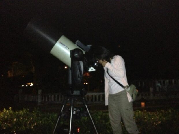 Guest looking through a computerized telescope at the night sky on Oʻahu