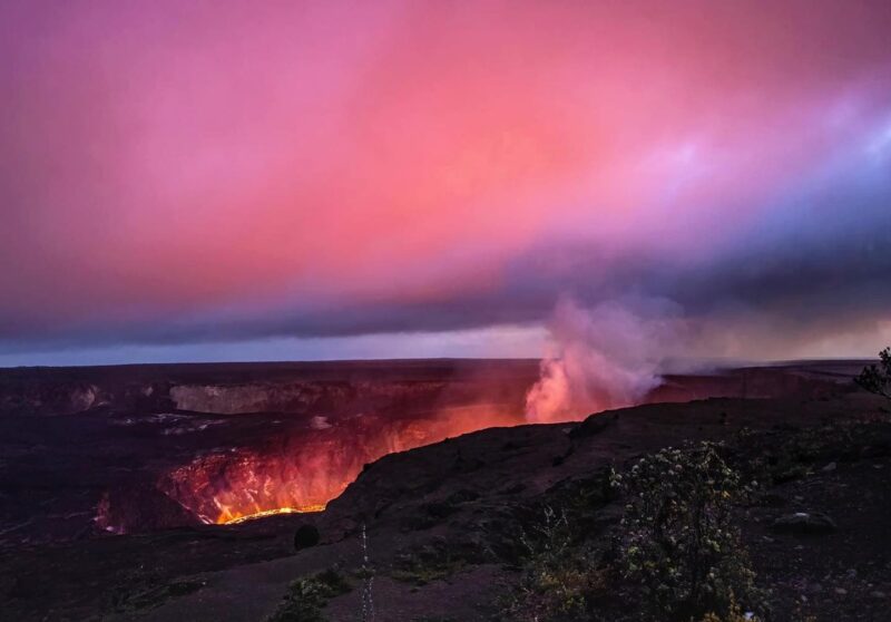 The sunset paints the sky above the Halemaʻumaʻu lava lake in the Hawaii Volcanoes National Park