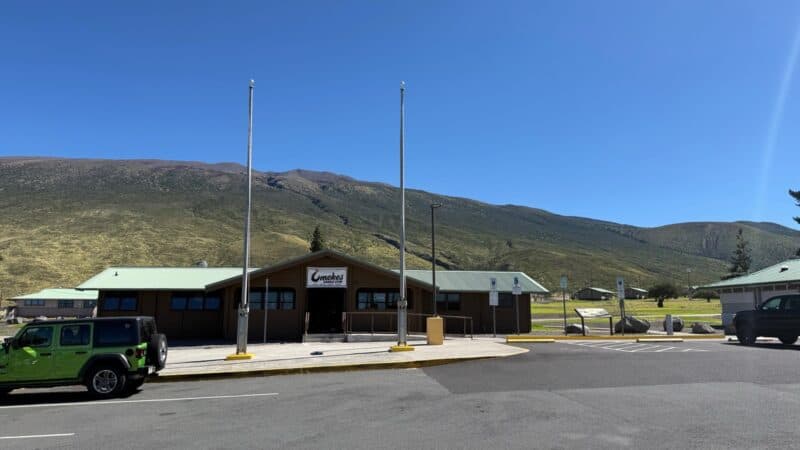 Umekes Saddle Stop, a log building with a green roof at the Gilbert Kahele Recreation Area on Saddle Road, Mauna Kea behind