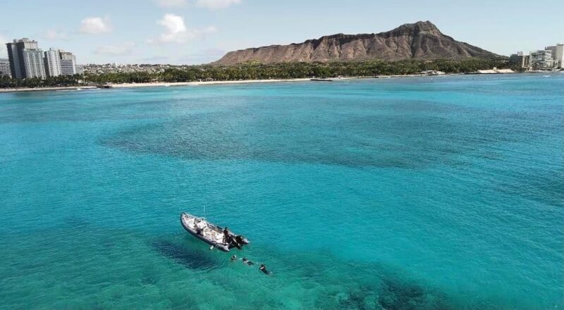 waikiki shoreline and diamond head as seen from the ocean with a speedboat in the foreground