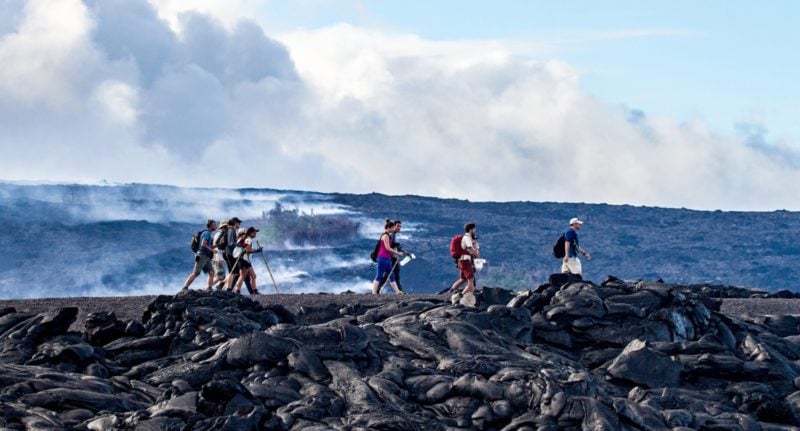 tour group hiking over lava