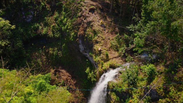 Waterfall in a steep gulch with a zipline cable crossing above it