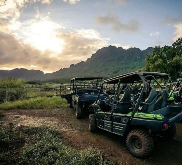 Parked Kawasaki UTVs with a mountain backdrop on the Kipu Ranch Kauaʻi tour
