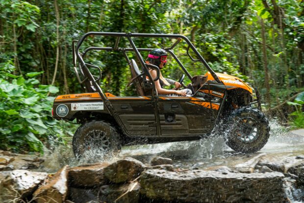 A Kawasaki UTV splashing through a water crossing on the Kauaʻi ranch tour