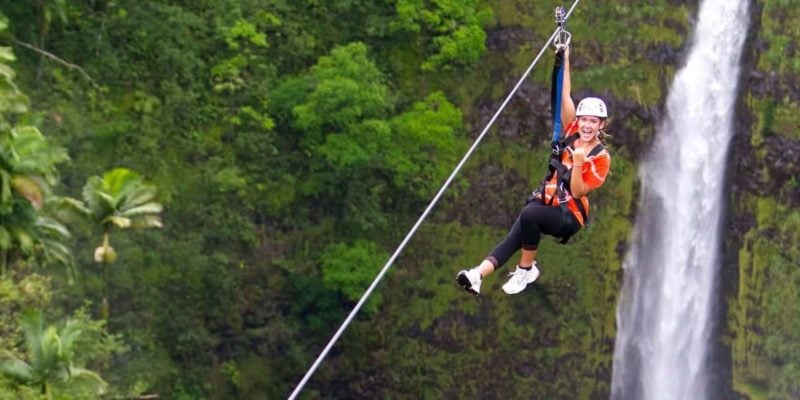 person ziplining in front of kolekole falls on Big Island, Hawaii.