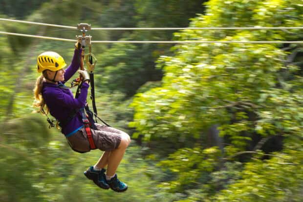 Zipline rider crossing the forest canopy with the background blurred by speed