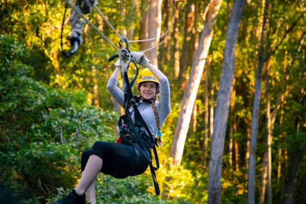 Zipline rider with a gloved hand on the trolley in the Kohala forest